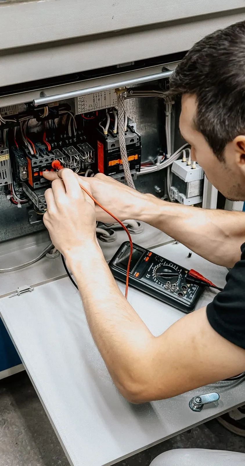 Électricien contrôlant un tableau électrique au multimètre